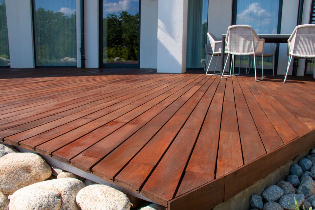 Terrasse bois moderne et mobilier d'extérieur pour jardin Terrasse en bois exotique rouge-brun devant une façade blanche moderne avec mobilier d'extérieur en osier.