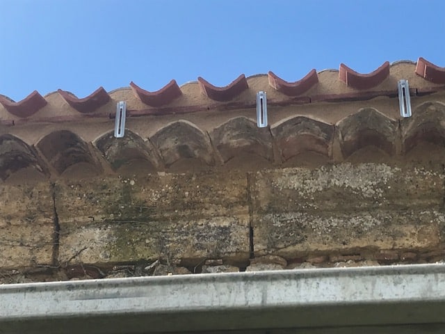 Supports métalliques pour toiture en tuiles et mur pierre Crochets de fixation métalliques installés sur une toiture en tuiles rouges et un vieux mur de pierre.