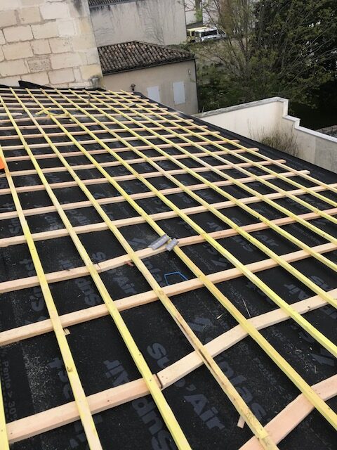 Pose de liteaux sur écran de sous-toiture Siplast Grillage de liteaux en bois sur un écran de sous-toiture Siplast noir lors de travaux de charpente.